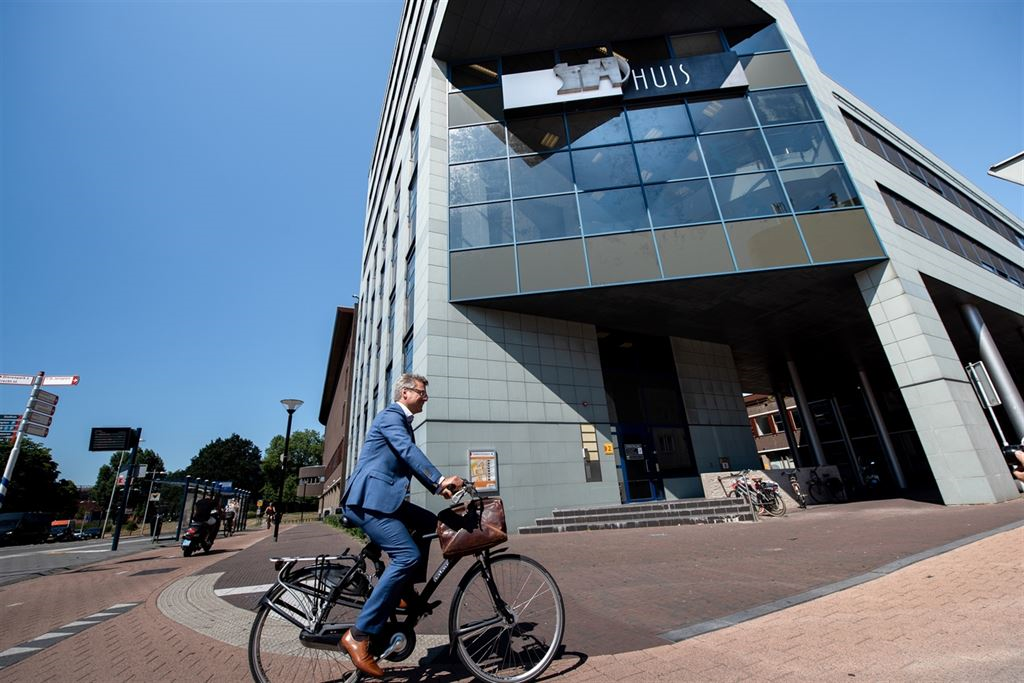  Tekst bij foto voor slechtzienden: Foto van een voorbijganger die langs het stadhuis fietst. 